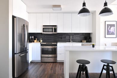 Bright, contemporary kitchen in Venice featuring white cabinetry, stainless steel fridge, oven, and.