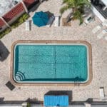Outdoor swimming pool with lounge chairs and shaded seating area.