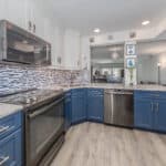 Bright, contemporary kitchen featuring blue lower cabinets, white upper cabinets, and modern applian.