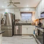Kitchen with stainless steel fridge, oven, microwave, and granite countertops.