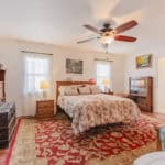 Spacious bedroom featuring a large bed, ceiling fan, and natural light in Port Charlotte home.