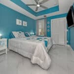 Blue bedroom with ceiling fan, flat-screen TV, and stylish decor in a Venice, Florida home.