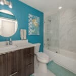 Bathroom with blue accent wall, modern vanity, and glass-enclosed shower in Venice, Florida.