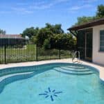 Pool in backyard at 1606 Cypress Point Court Venice FL, with lush greenery and sunny sky.